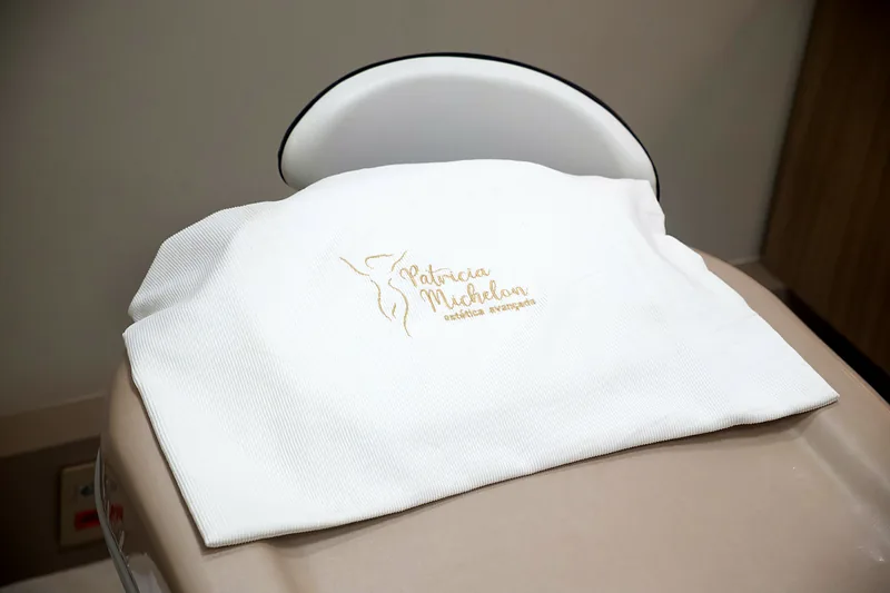 Manta branca com o logotipo bordado em dourado sobre a maca.